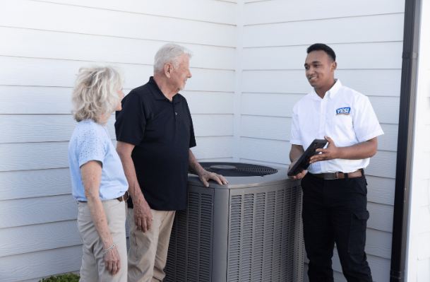 Smiling YES! technician speaking to older couple about hvac repair at their Las Vegas home outside. 